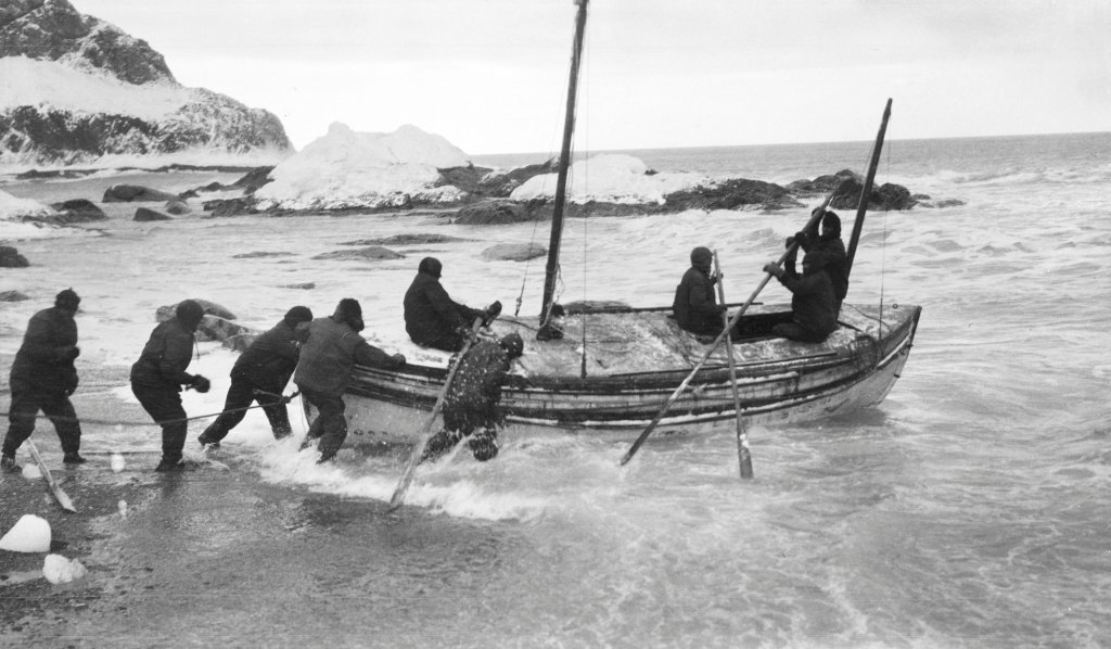 Six men launch a small boat out to sea