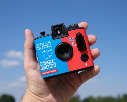 Photograph of the Lomography Half-frame Simple Use Camera held in one hand, facing front with lens and flash control visible