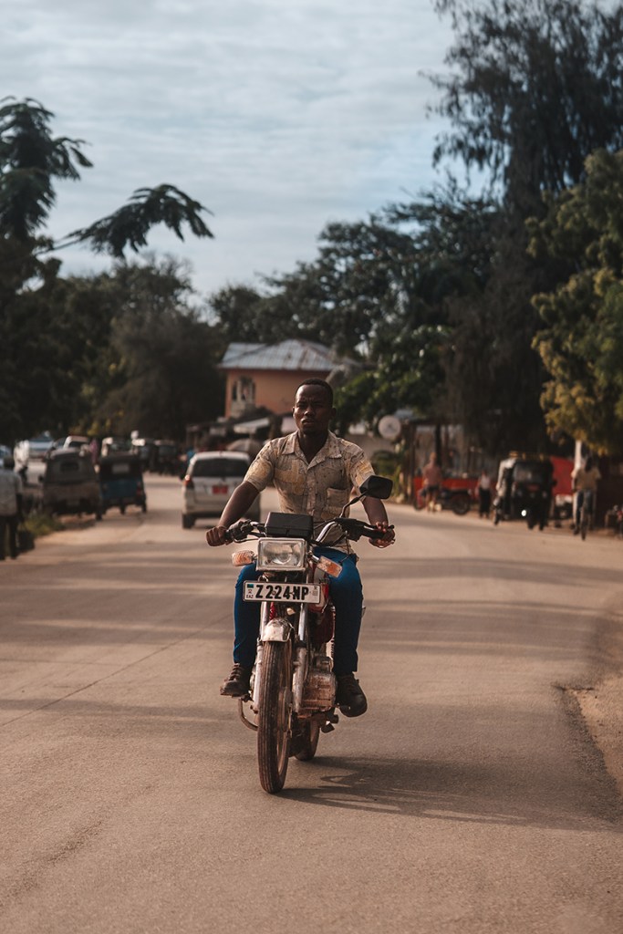 A man rides a classic motorcycle on the dusty roads of Paje village Sony A7IV, Sigma 56mm f1.4 Lens, f2 at 1/6400