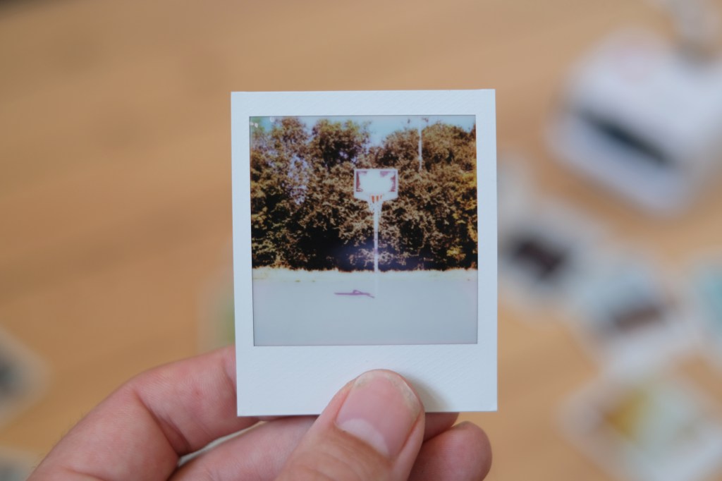 Overexposed Polaroid Go photograph of a basketball hoop in sunlight.