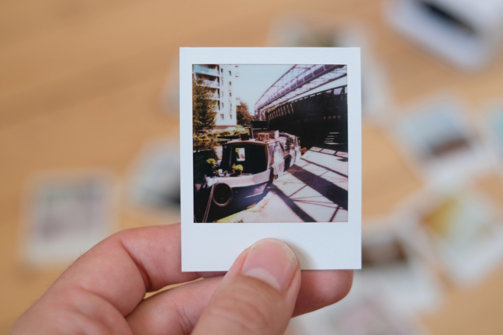 Polaroid Go photograph of a boat on a river under a bridge