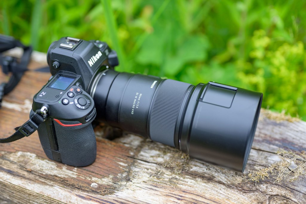 Top down, three quarters view of the Tamron 90mm F2.8 Di III Macro VXD lens with lens hood, mounted on a Nikon Z8 camera