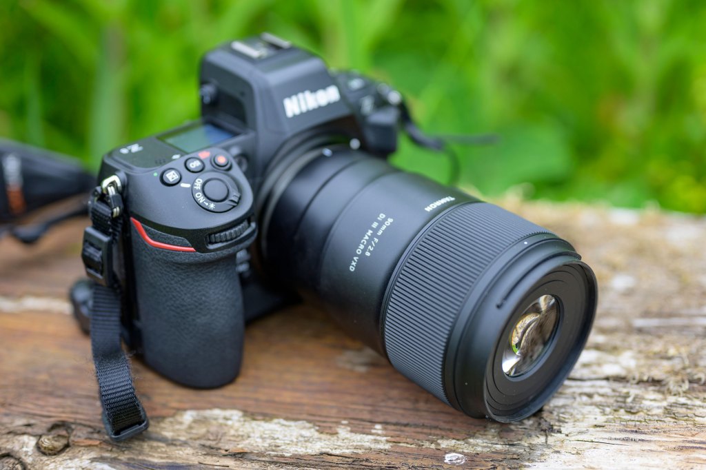 Top down, three quarters view of the Tamron 90mm F2.8 Di III Macro VXD lens mounted on a Nikon Z8 camera