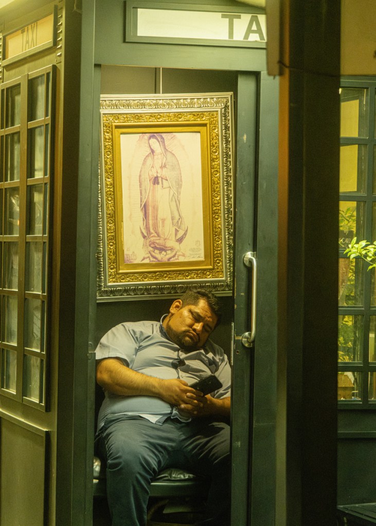 man asleep in a telephone box