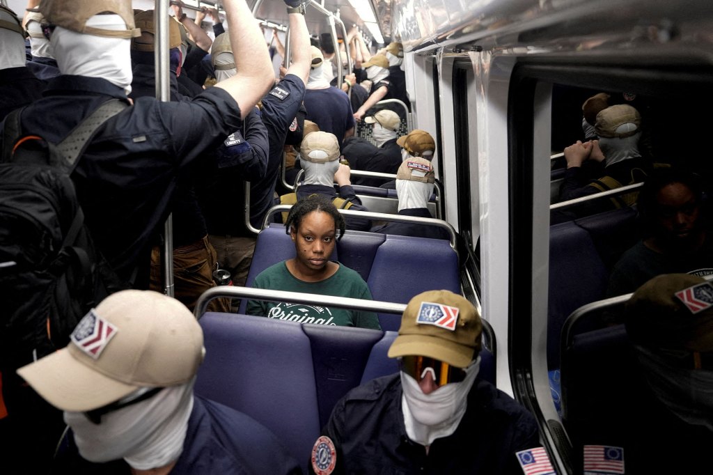 A commuter sits as members of the group Patriot Front ride the metro on the Fourth of July in Washington. REUTERS/Cheney Orr