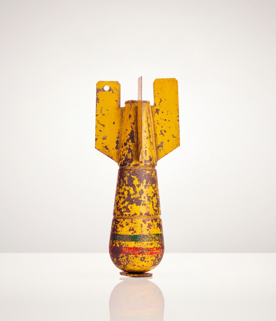 ‘Objets d’Mort’ is the first body of work in the series ‘The Things They Carried’ which explores war through individual items. In these large-scale still-lives, Duley revisits his early work as a fashion photographer to present these devices as seductive, commercial items. Glossy advertising images of items designed to kill and maim’ the apparatus of violence. Image Credit: Giles Duley