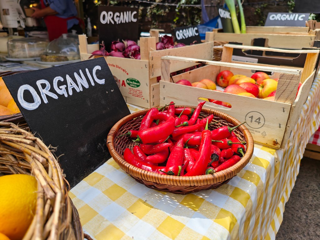 Honor Magic V6 sample. a table at a market with red peppers and other goods on it