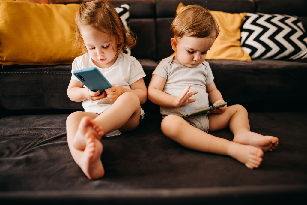 Two small children using smartphones