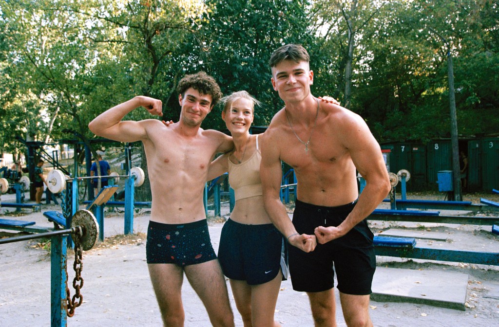 Ruslan, Maryna, Danyl. Kachalka open air gym Kyiv, Ukraine. August 2024. Shot on an old Contax G2 film camera and Kodak Portra 400 film. Image Credit: Giles Duley